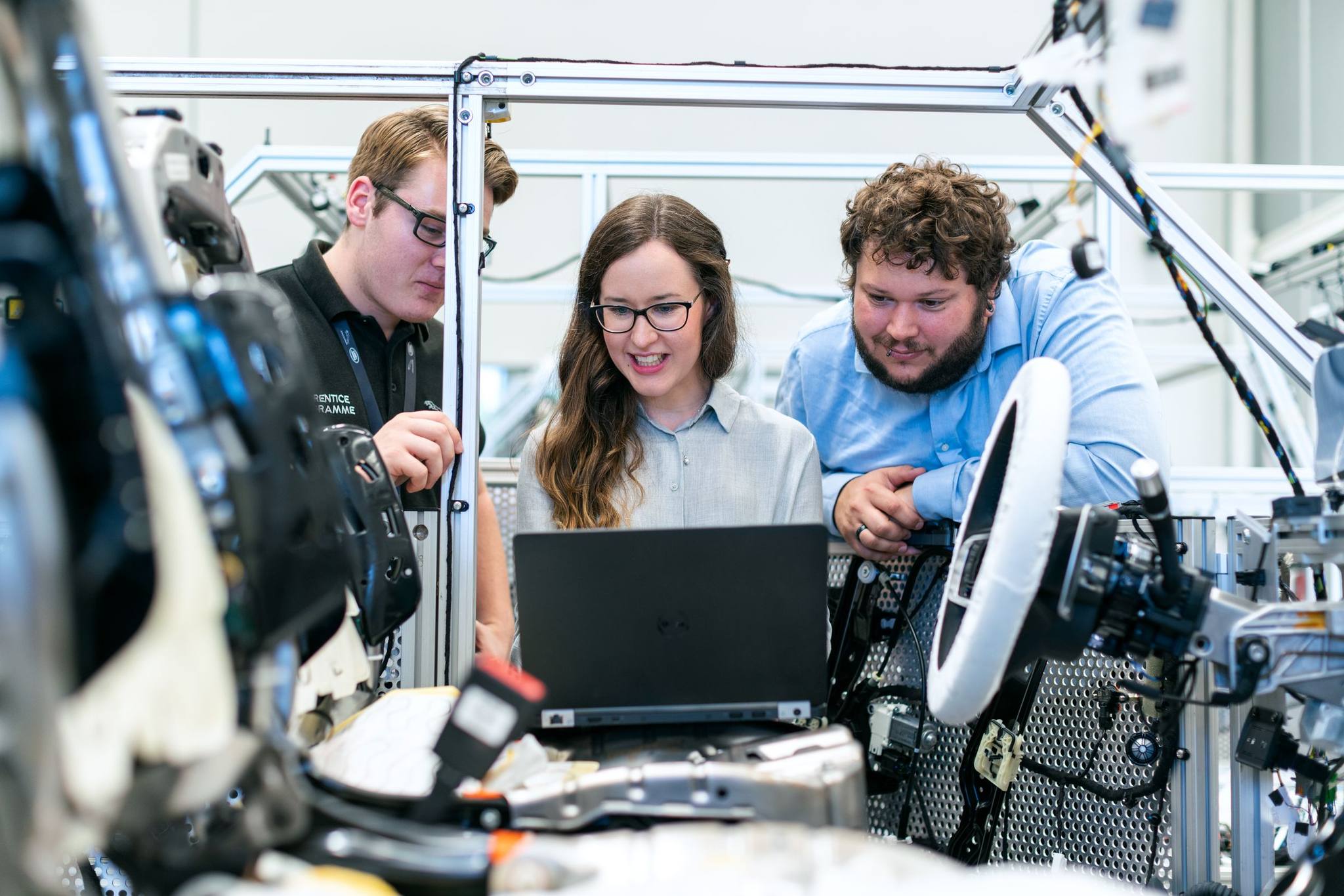 Three engineers gathered round a laptop at a robotics test rig